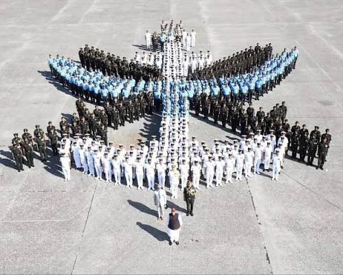 Aerial view of personnel from army, navy and air force units arranged in a large star-shaped formation on a parade ground.